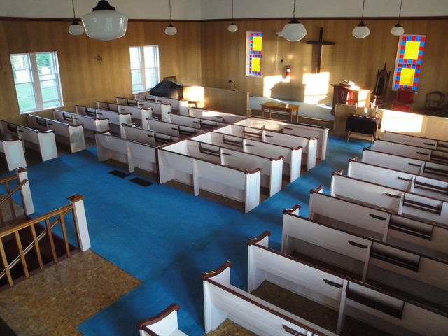 一个古老的教堂圣所，蓝色的地毯，白色和棕色的长凳，祭坛上有一个十字架