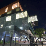 这是中央图书馆夜间的美丽照片，从地面向上看，房间亮着灯，外面有一辆自行车