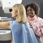 一位黑人女放射科医生和一位白人妇女在乳房x光检查机前