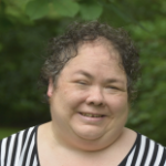 一个微笑的女人，一头黑色的短卷发，穿着条纹T恤