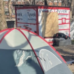 a tent and a wooden shelter in a muddy park on a winter day