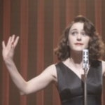 A woman on a stage with a microphone red backdrop