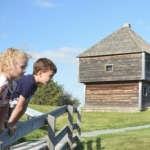 两个孩子越过栅栏望向一座历史悠久的堡垒