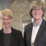 两名身穿黑色西装的白人妇女在政府大楼内