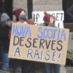 抗议者举着一个牌子，上面写着新斯科舍省应该加薪!