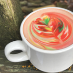 A coffee in a white mug with multi coloured foam on top