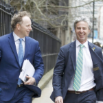 Two white male politicians walking down the street laughing