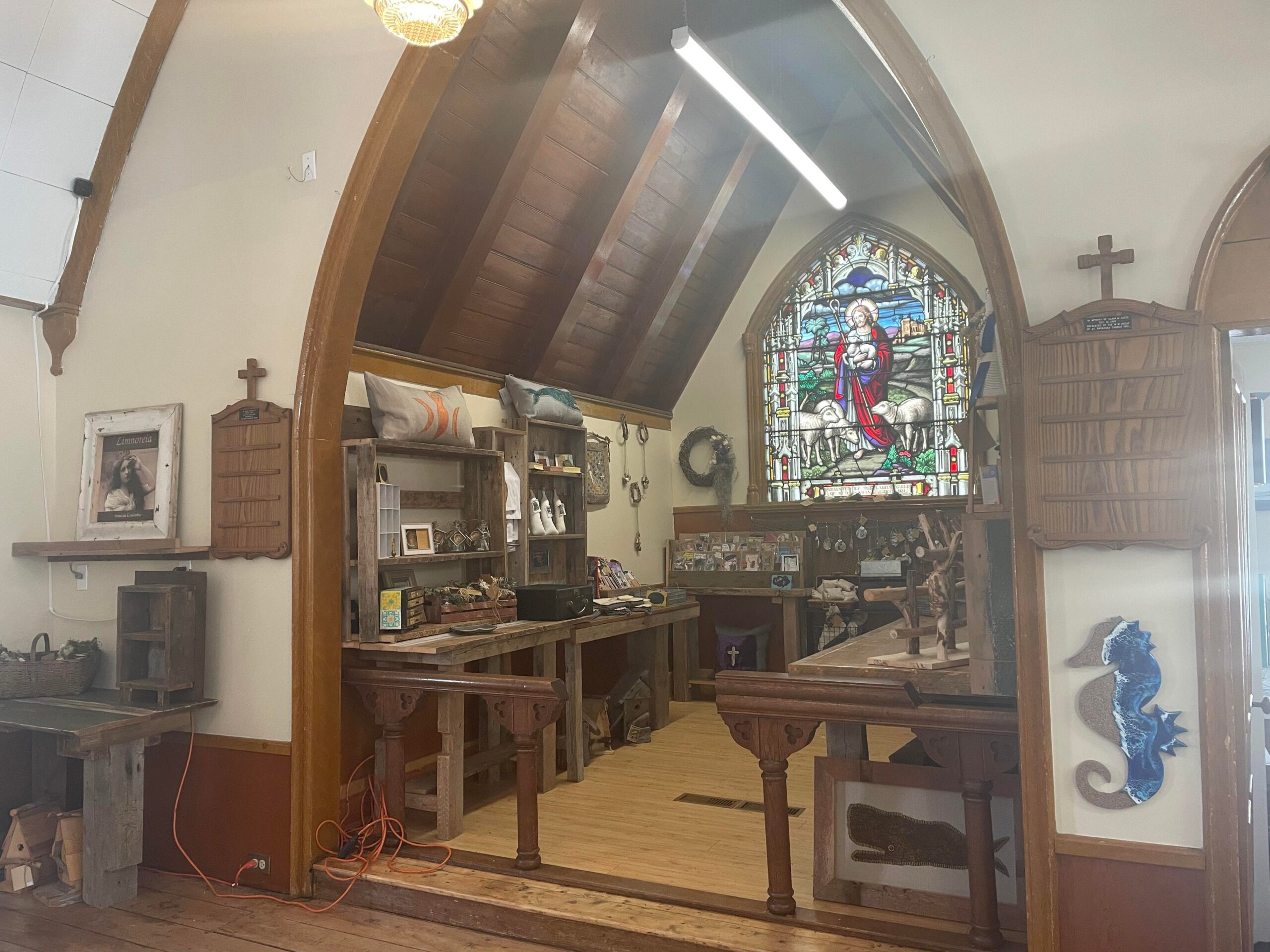 一座教堂的旧祭坛焕然一新，摆满了艺术展品。背景是带有耶稣图案的彩色玻璃窗