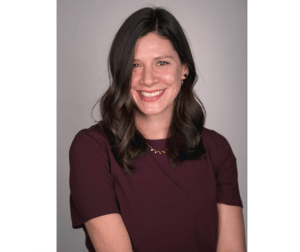 有中长黑发的一个微笑的妇女和一个勃艮第的短袖毛线衣在米黄背景的照相机微笑。