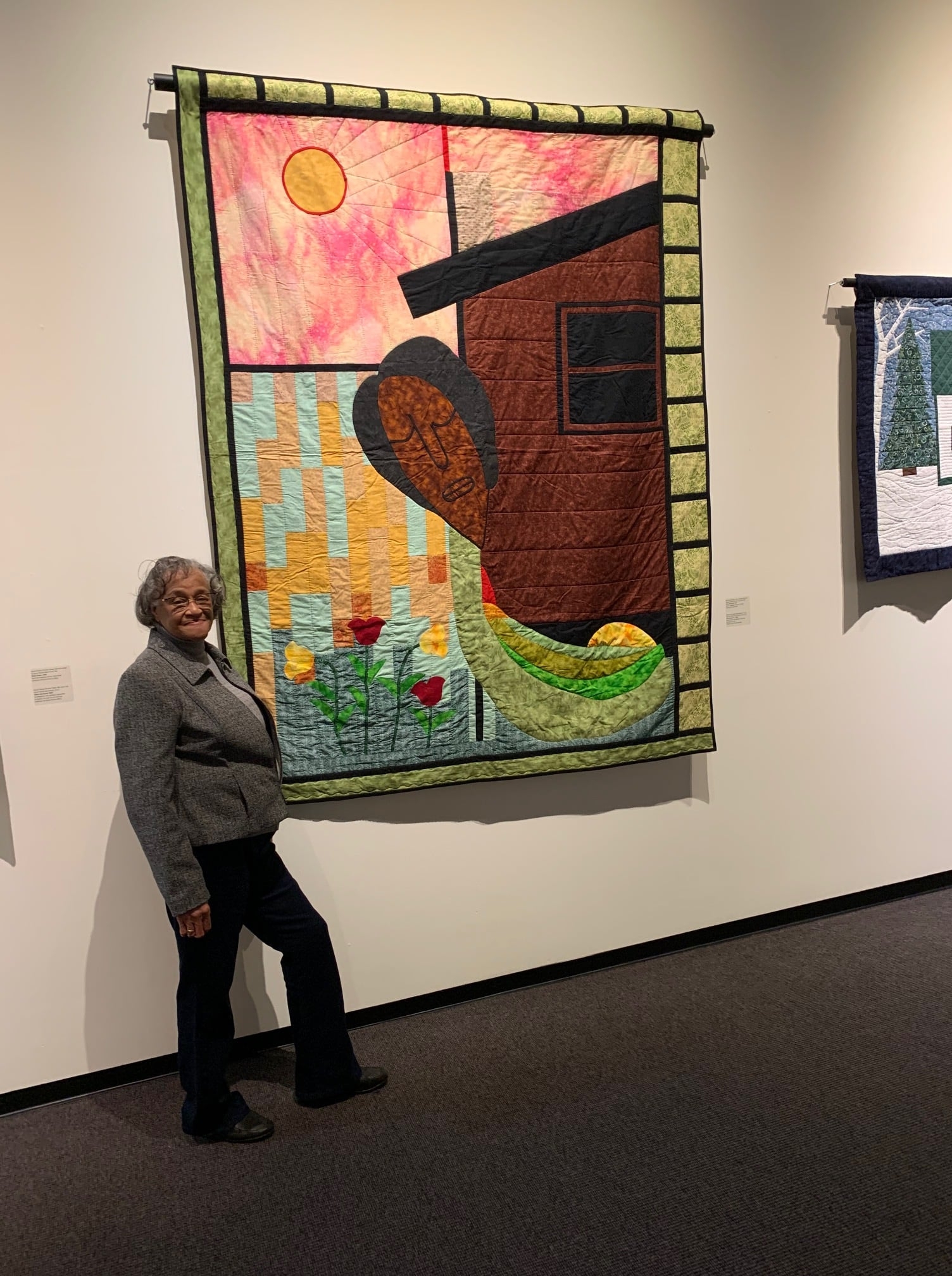 一位年长的黑人女士在非洲新斯科舍被子旁摆姿势