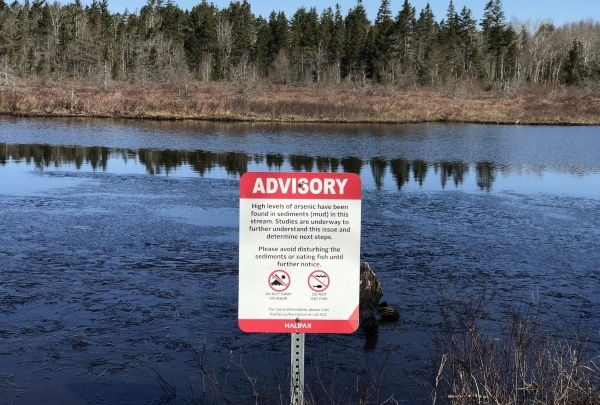 一个顾问警告说对高水平的一个标志rsenic, in front of a body of water