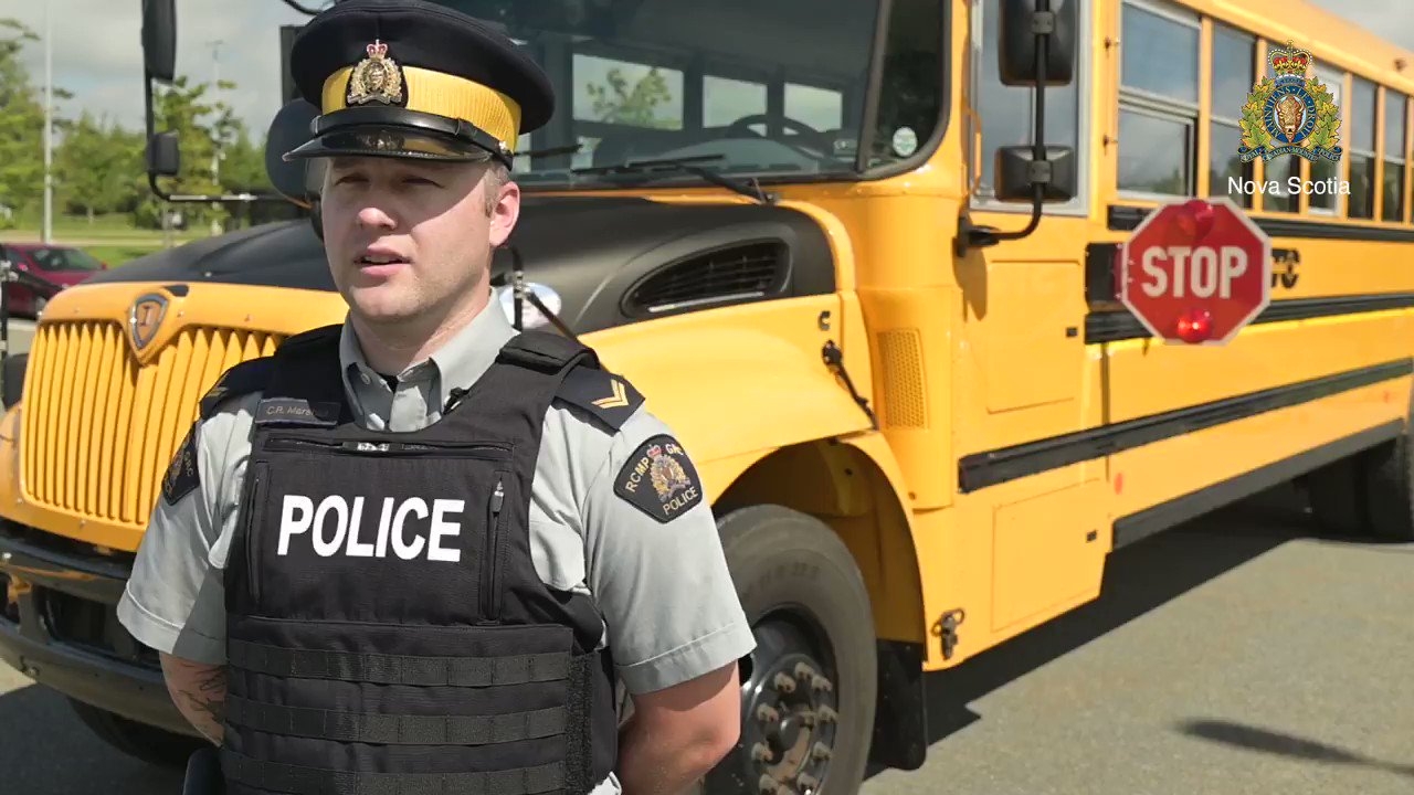 Police officer in black bullet proof police vest with yellow school bus in the background