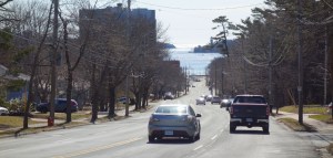 一天的时间。两辆车开向乔豪大道的西北方向。手臂在远处隐约可见。这条街的人行道两旁都是光秃秃的树。