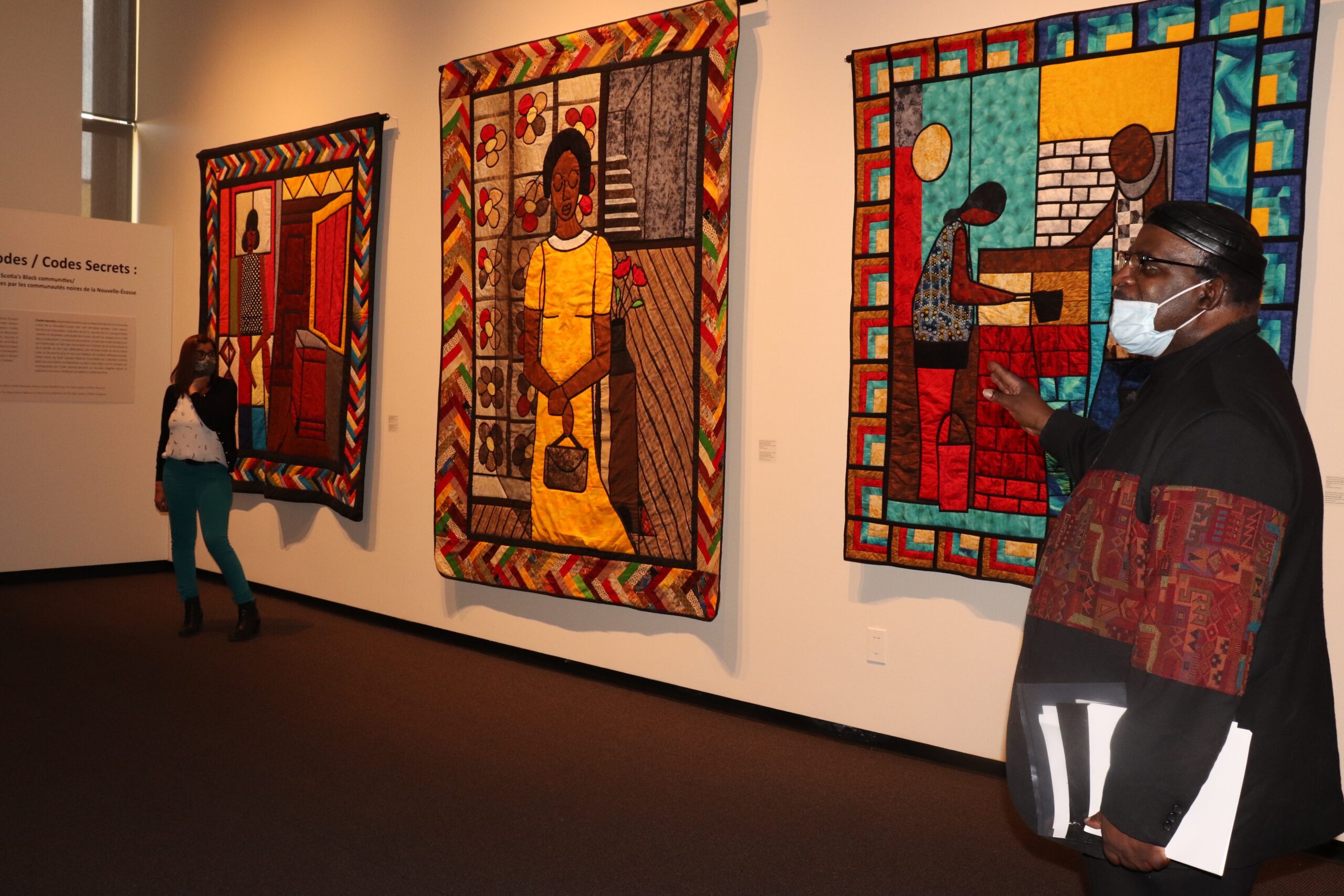 一名男子在画廊的墙上展示五颜六色的被子。