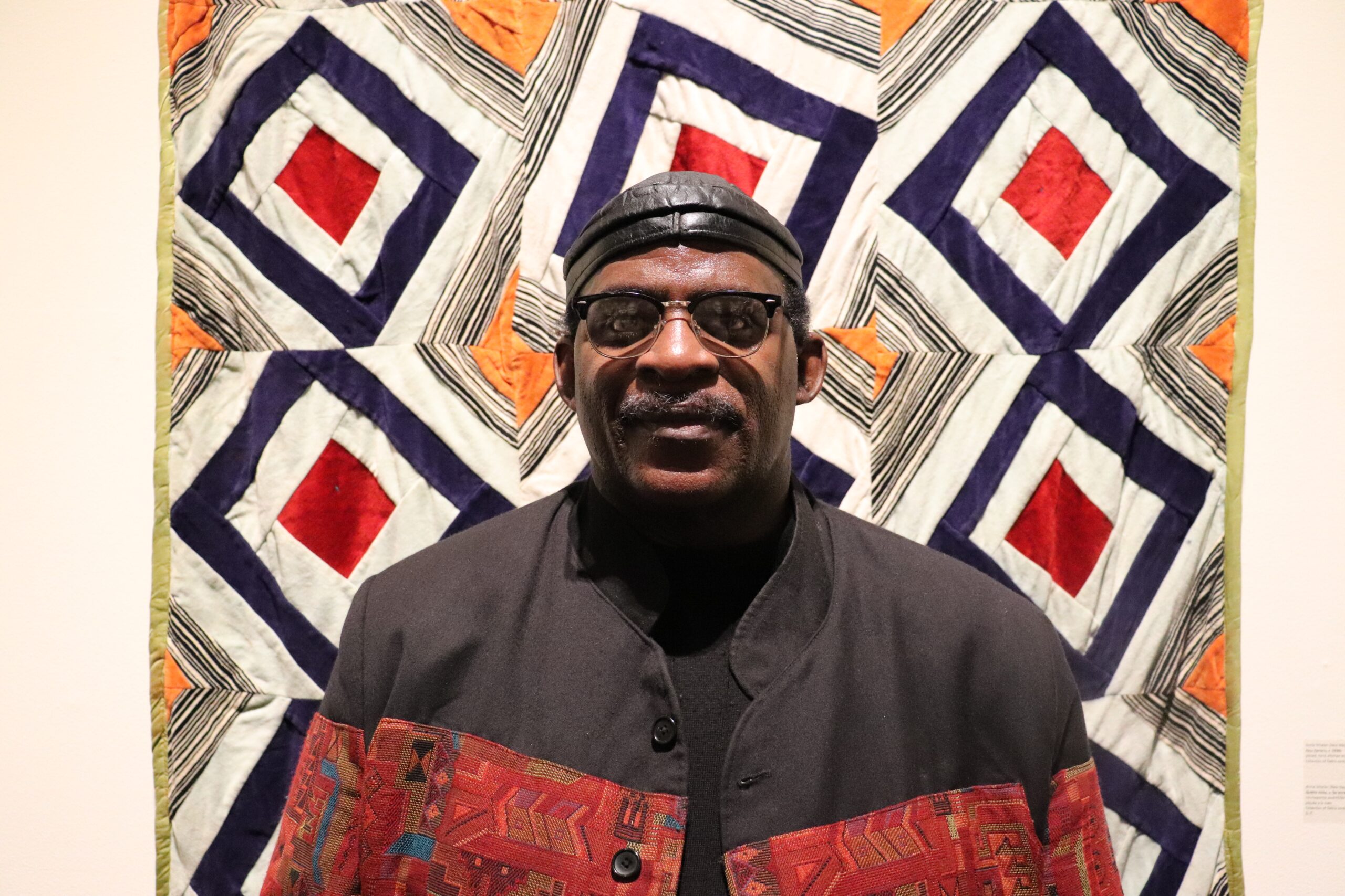 戴着黑帽子和眼镜的黑人男子在非洲新斯科舍被子前摆姿势。