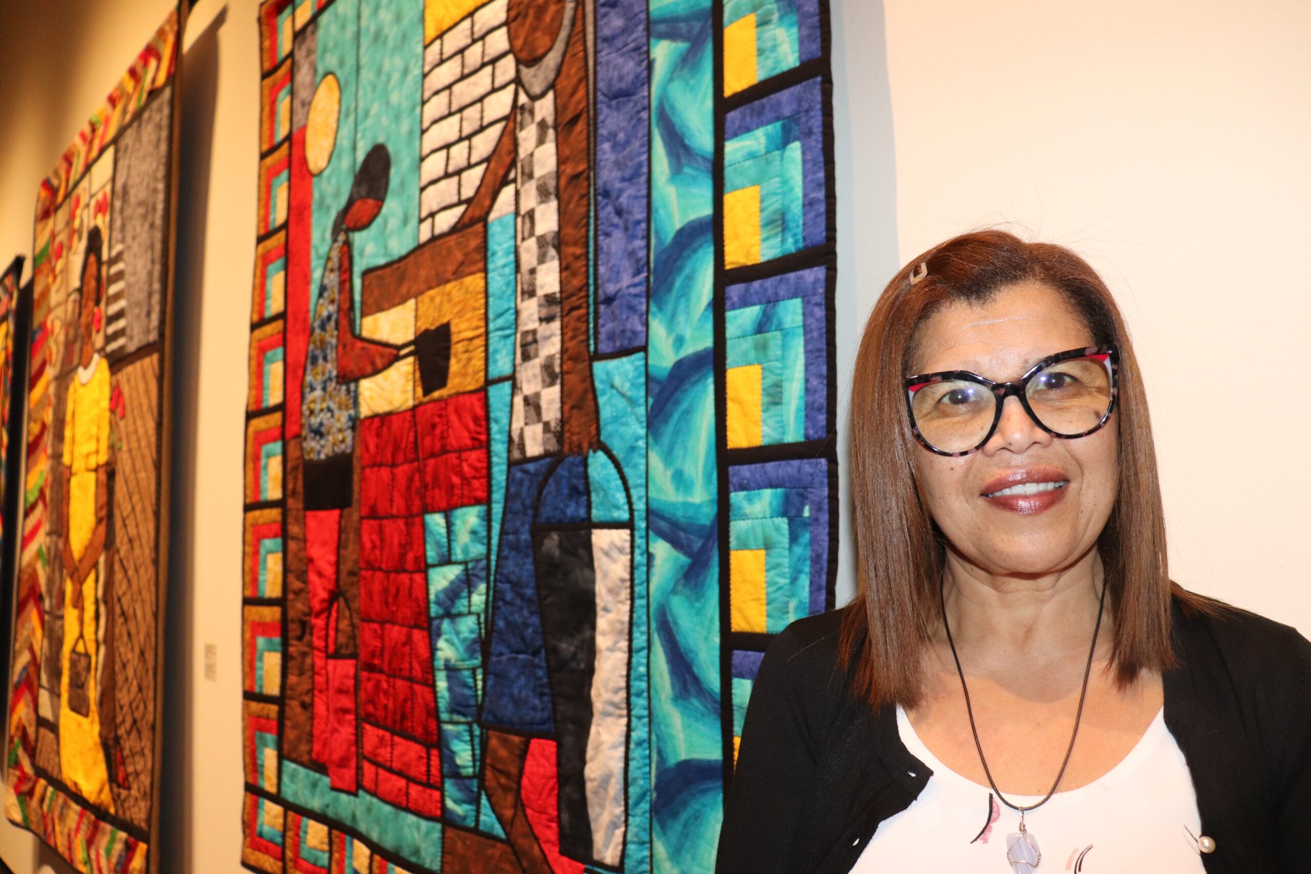 戴眼镜的黑人女士在非洲新斯科舍被子前摆姿势。