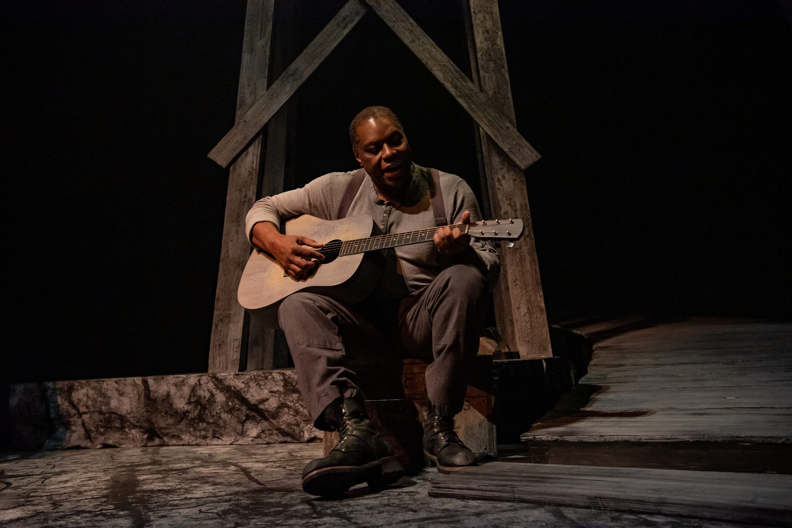 一个演员在舞台上边弹吉他边唱歌