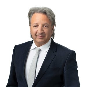 一个白发男子的头像，身穿黑色西装，白色衬衫，打着灰色领带。