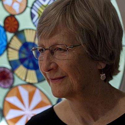 在彩色玻璃窗前微笑的白人妇女。