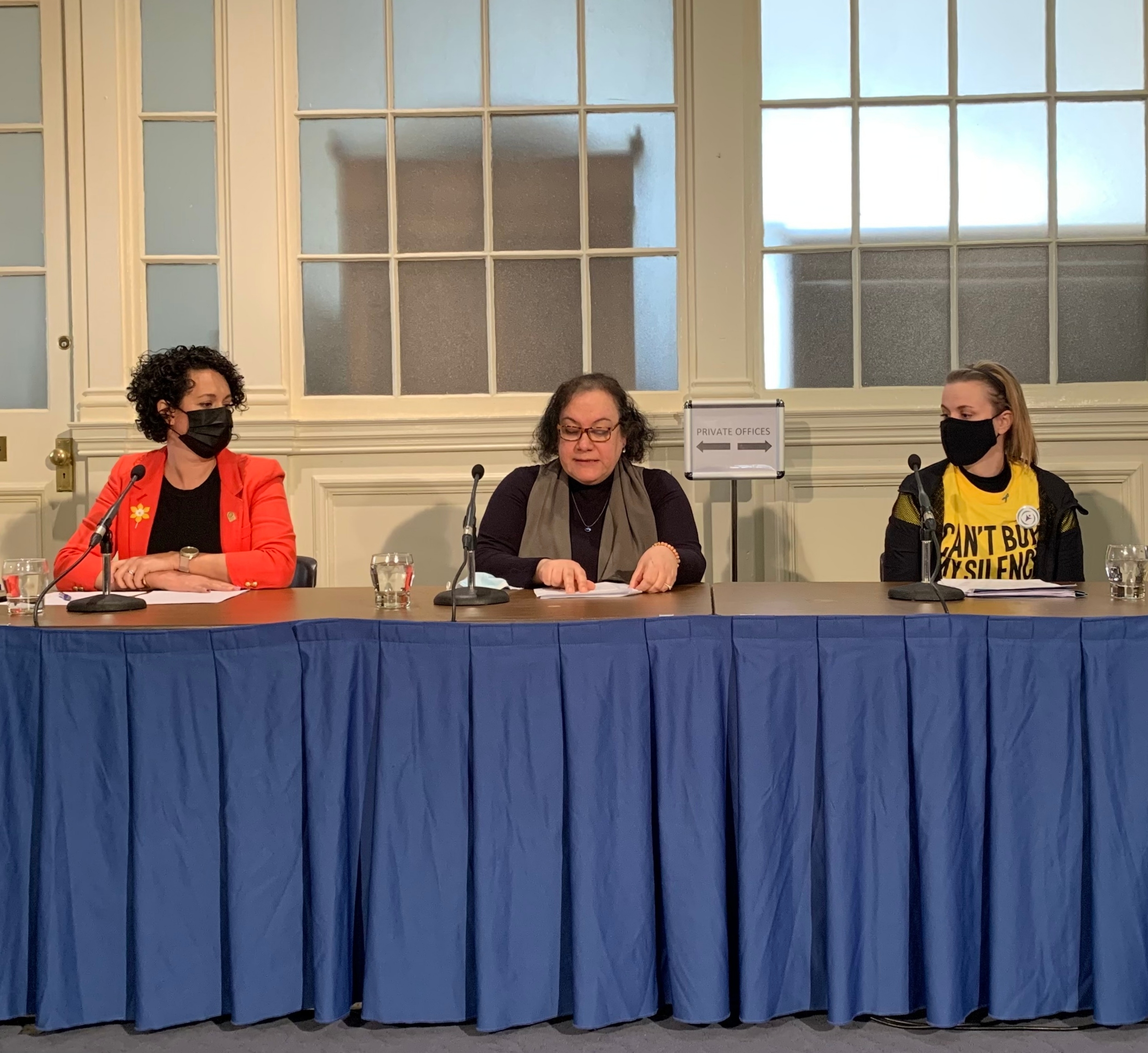 三个女人拿着麦克风坐在一张桌子旁。