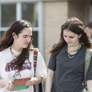 A scene from the film Night Blooms, with two young white women in front of a high school.