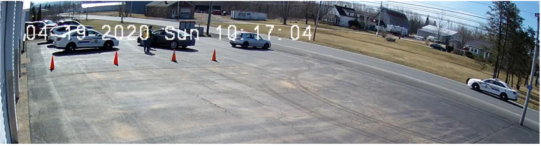 两名男子站在停车场，一辆假警车驶过