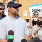 一名戴着黑色棒球帽的白人男子接受记者采访