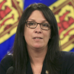 一名黑发女子站在一面墙的新斯科舍省旗帜前