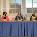 三个女人坐在一张桌子旁，拿着麦克风