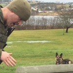 一个穿着绿色警服，带着警犬的男人