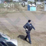 一个警察走在碎石停车场里