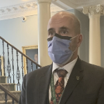 一个秃头男人，戴着黑蓝相间的面具，穿着深色西装