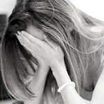 一个白人女人双手捂着脸，痛苦不堪