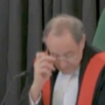 一位年长的男法官在法庭上调整眼镜