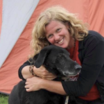 一个金发女人带着她的黑狗微笑