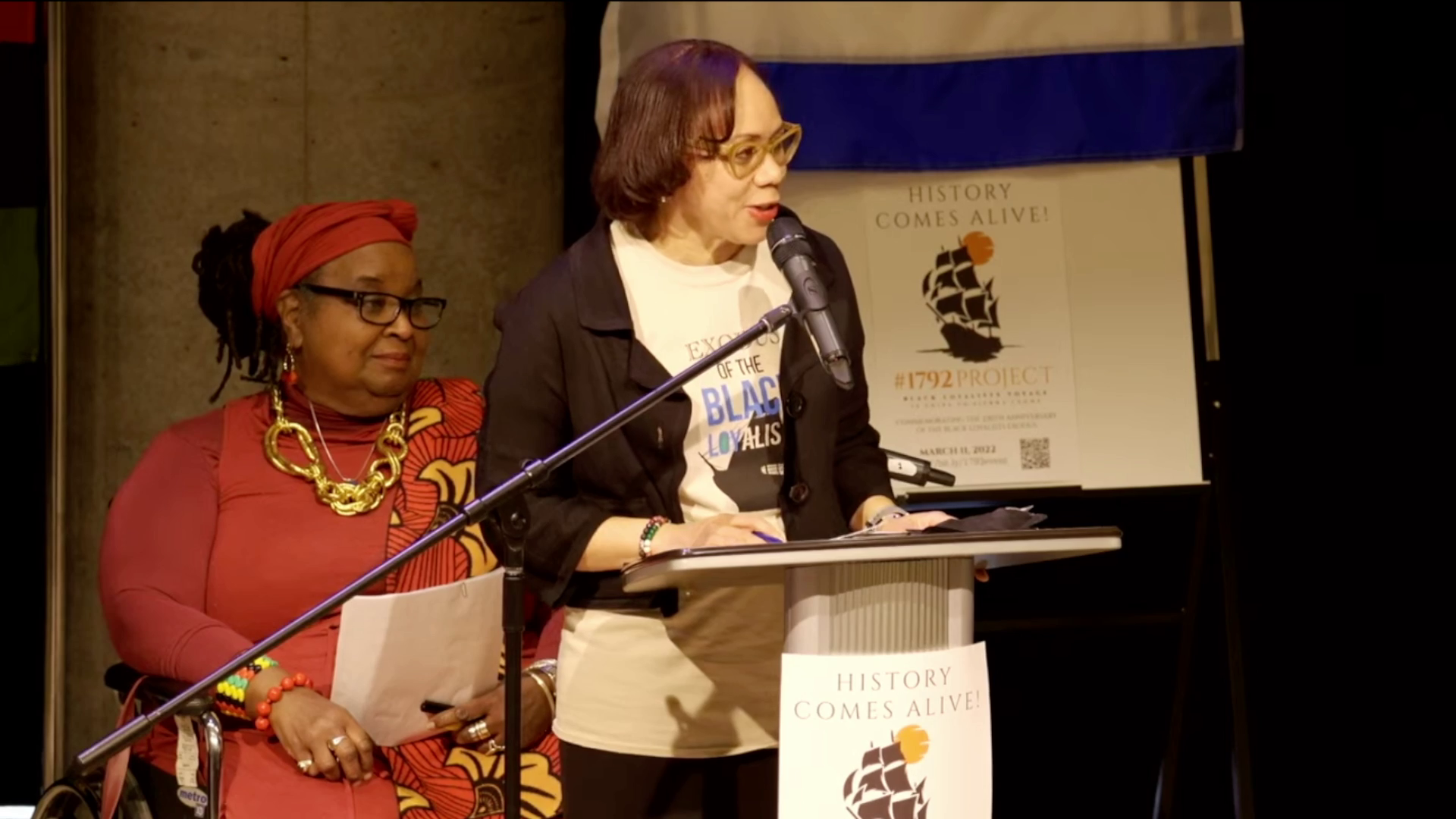 2022年3月11日，在哈利法克斯中央图书馆，奥本大道高中校长和项目组织者凯伦·哈德森共同主持了“历史变得鲜活:15艘船到塞拉利昂#1792”，林恩·琼斯坐在背景中。