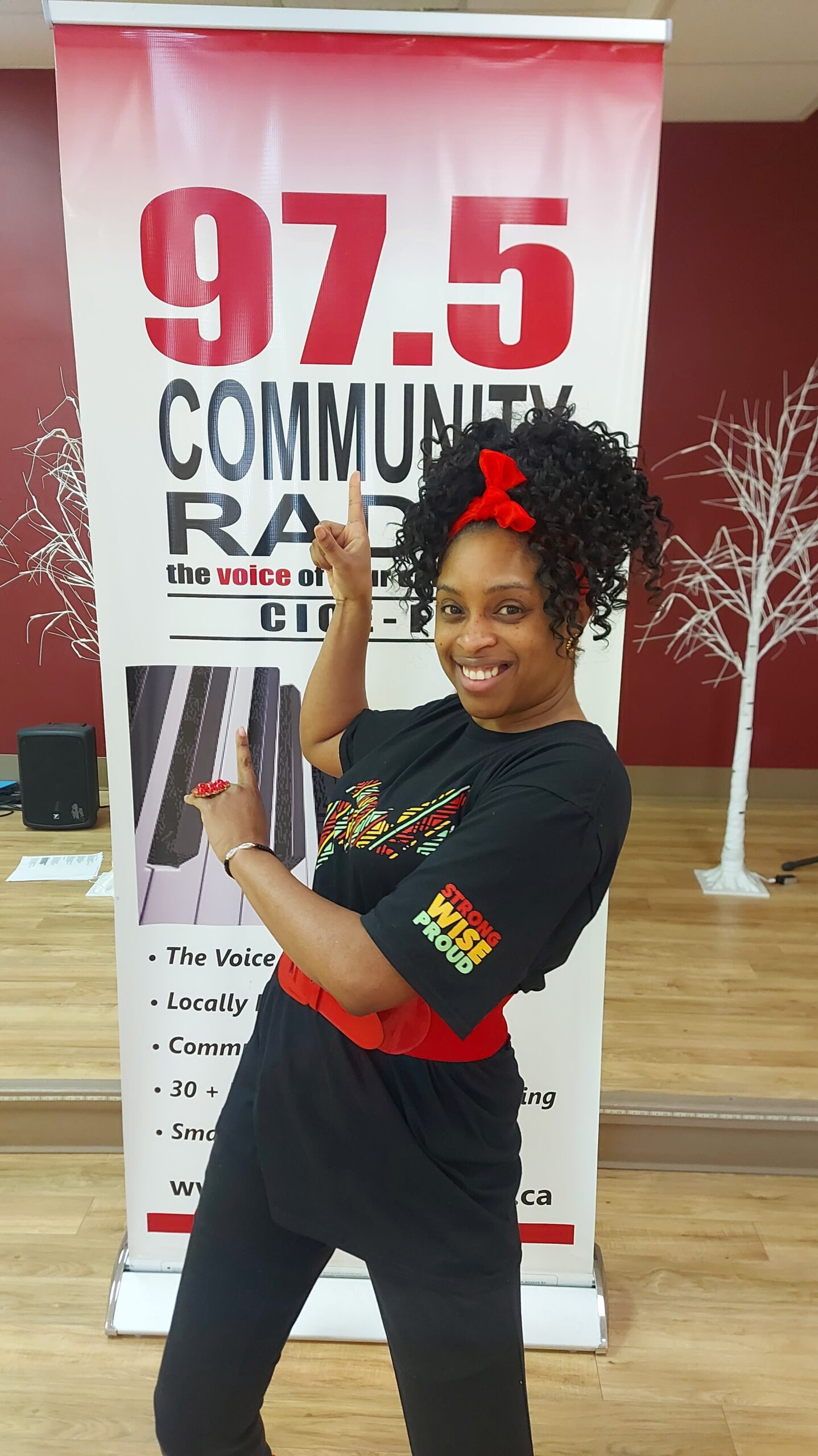 黑人妇女摆在广播电台促销海报前。