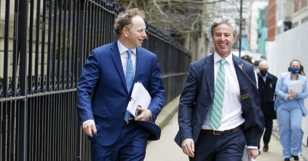 两个穿着蓝色西装的男人在街上走来微笑。