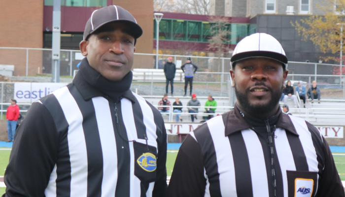 两名男子身穿黑白裁判服，头戴裁判帽。