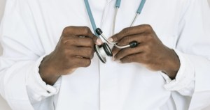 一个穿着白色白大褂的医生拿着听诊器的胸部特写。