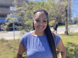 Black woman with long dark braids smiles for the camera on a sunny day