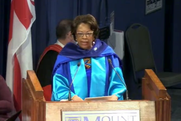 身穿蓝色毕业礼服的黑人女士在讲台上发表演讲