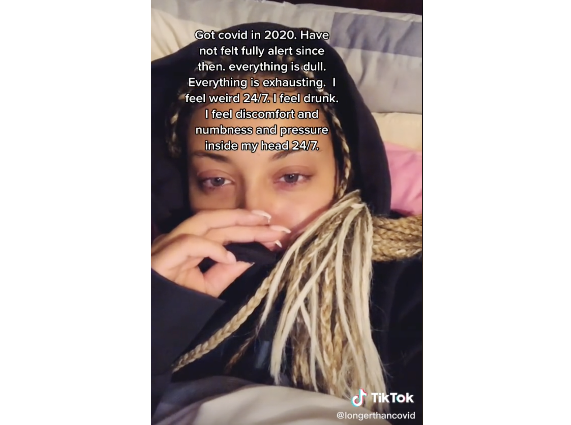 视频截图，一位年轻女性讲述了她的大脑健康如何受到长时间covid的影响。她用手捂着嘴，疲惫地看着镜头。