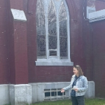 一个白人妇女站在一座红砖教堂前