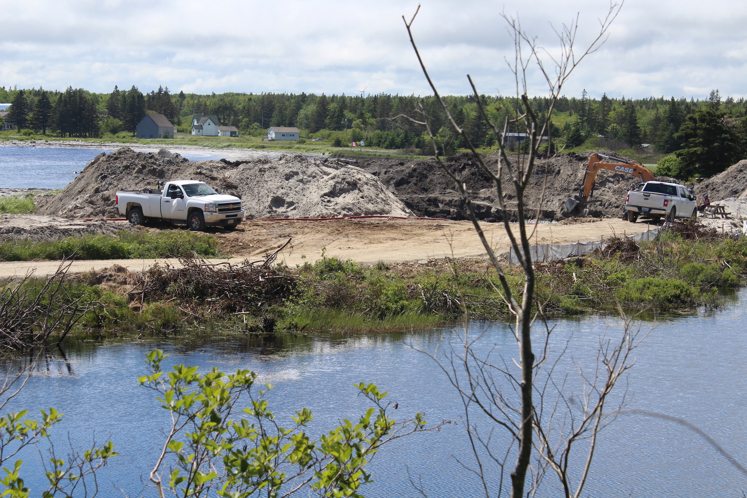 two pickup trucks and an excavator at a construction site
