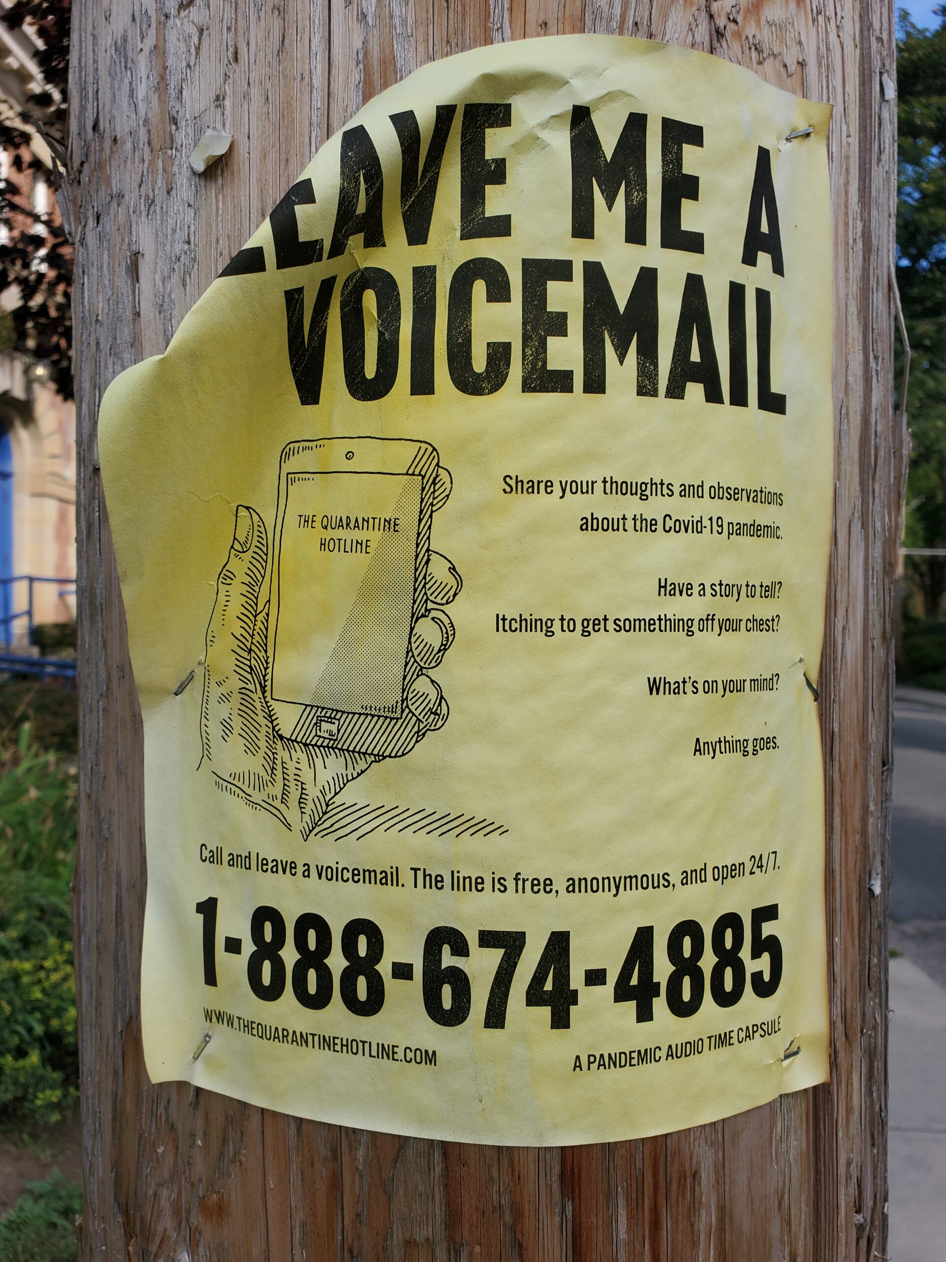 杆子上破旧的海报，画着一只手拿着电话，上面写着“给我留个语音信箱和电话号码”。