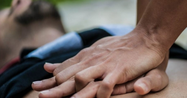 一个人的双手在地上对一个有胡子的男人进行胸部按压的特写。