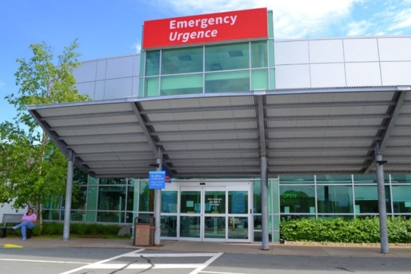 The front entrance of an emergency room with glass doors and an overhanging roof over the entrance. A red sign above the entrance reads 