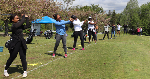 一排黑人妇女在高尔夫练习场挥杆