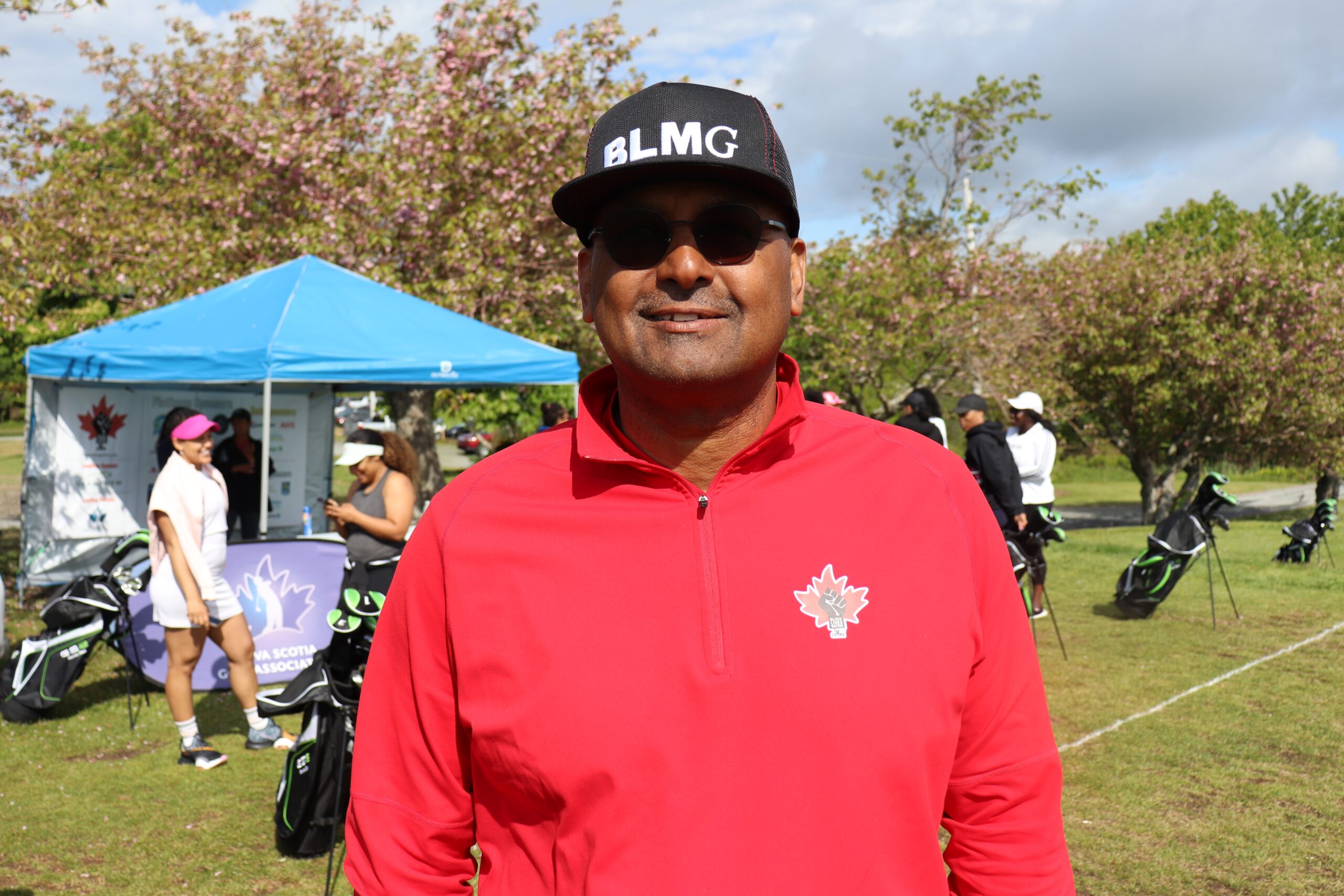 红色衬衫的黑人，黑色墨镜和黑色棒球帽，带有白色字母的“ blmg”